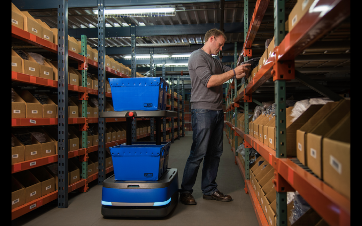 A Person Organising Industrial Goods with the help of warehouse robots.